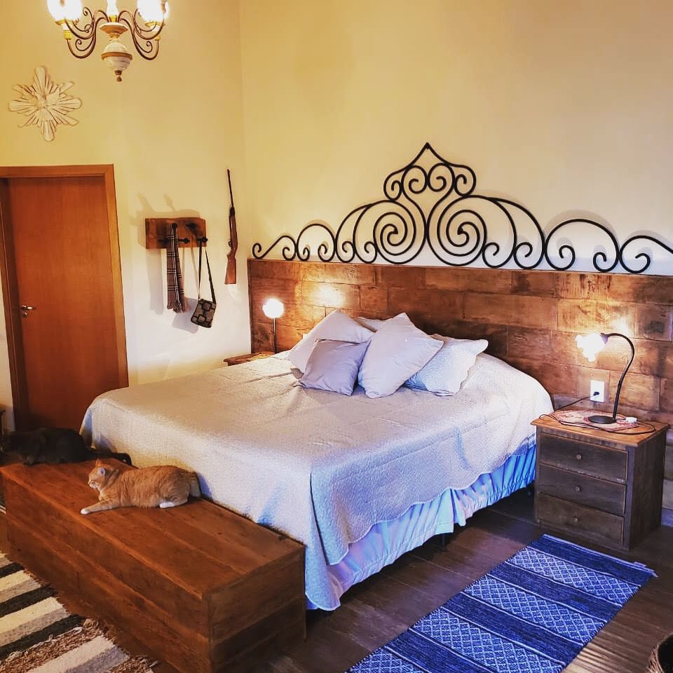 Quarto com cabeceira rústica, banco e mesas de cabeceira de madeira